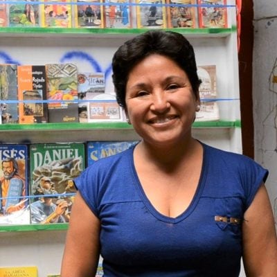 Flor stands in front of stand of books smiling