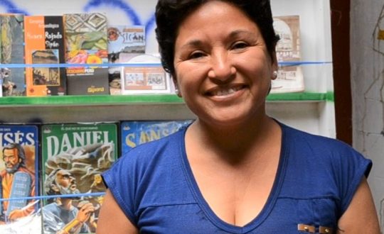 Flor stands in front of stand of books smiling