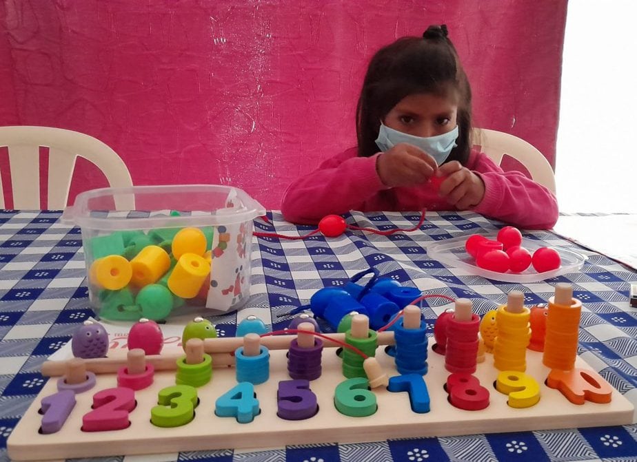 girl, approximately 6 years old, plays with coloured blocks