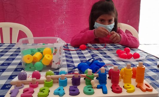 girl, approximately 6 years old, plays with coloured blocks