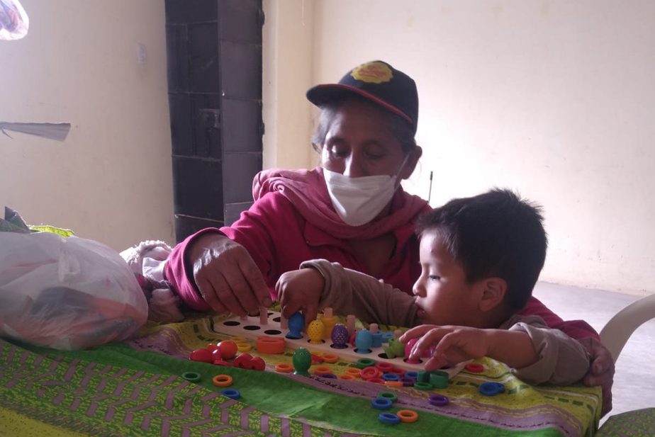 mother helps her son, a boy of about 6, with coloured blocks