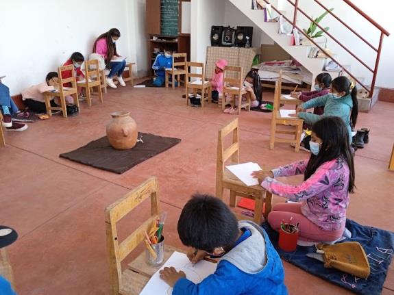 children sit in a circle around a clay pot, drawing it