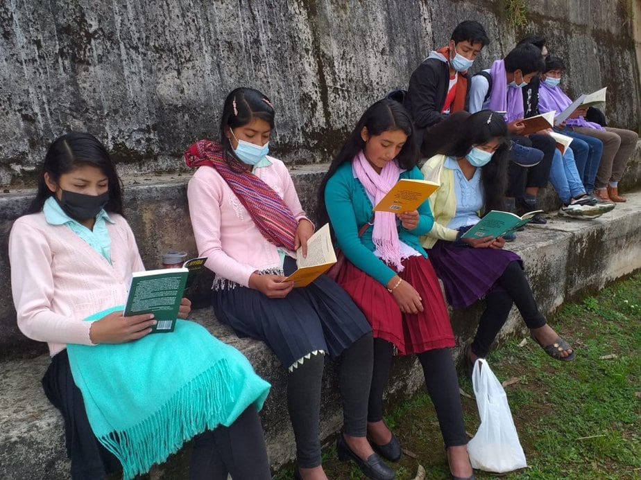 four indigenous girls sit along wall reading