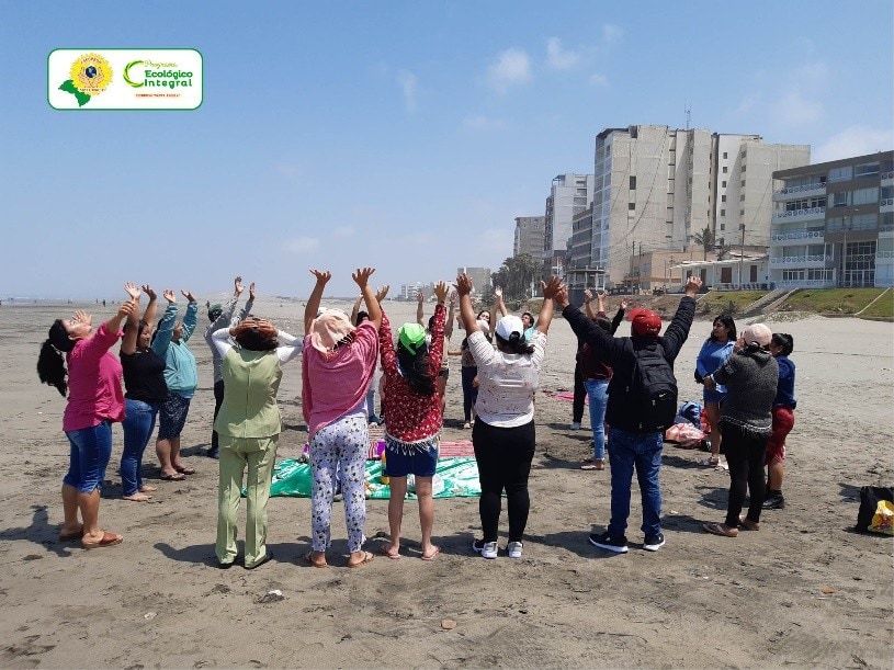 a circle of women on the beach lift their hands to the sky