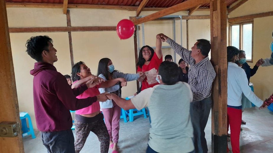 Men and women join hands to bounce a red balloon into the air