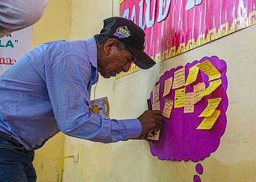 man sticks sticker with words on it onto a pink circle on the wall