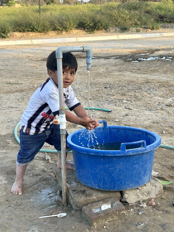 Little boy washing hands at tap