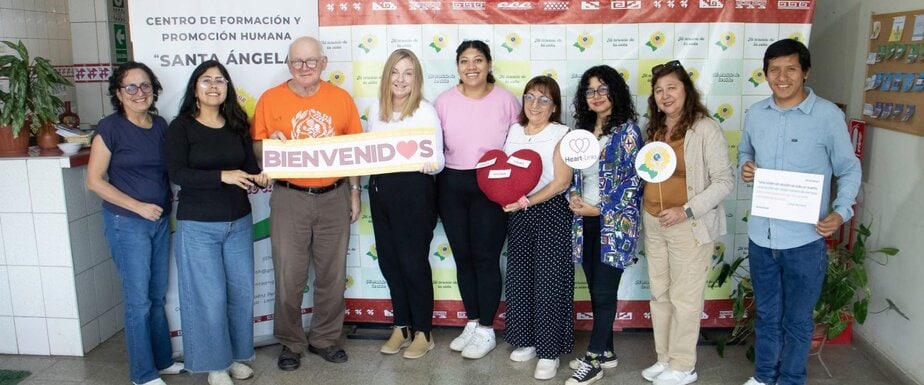 a row of men and women face the camera holding a sign that says bienvenidos