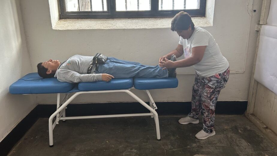 a woman lies on a cot while another woman massages her feet