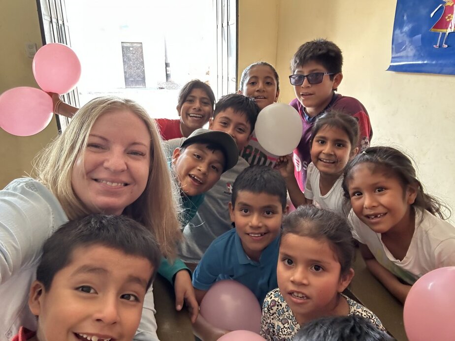 children and a woman gather together with white and pink balloons