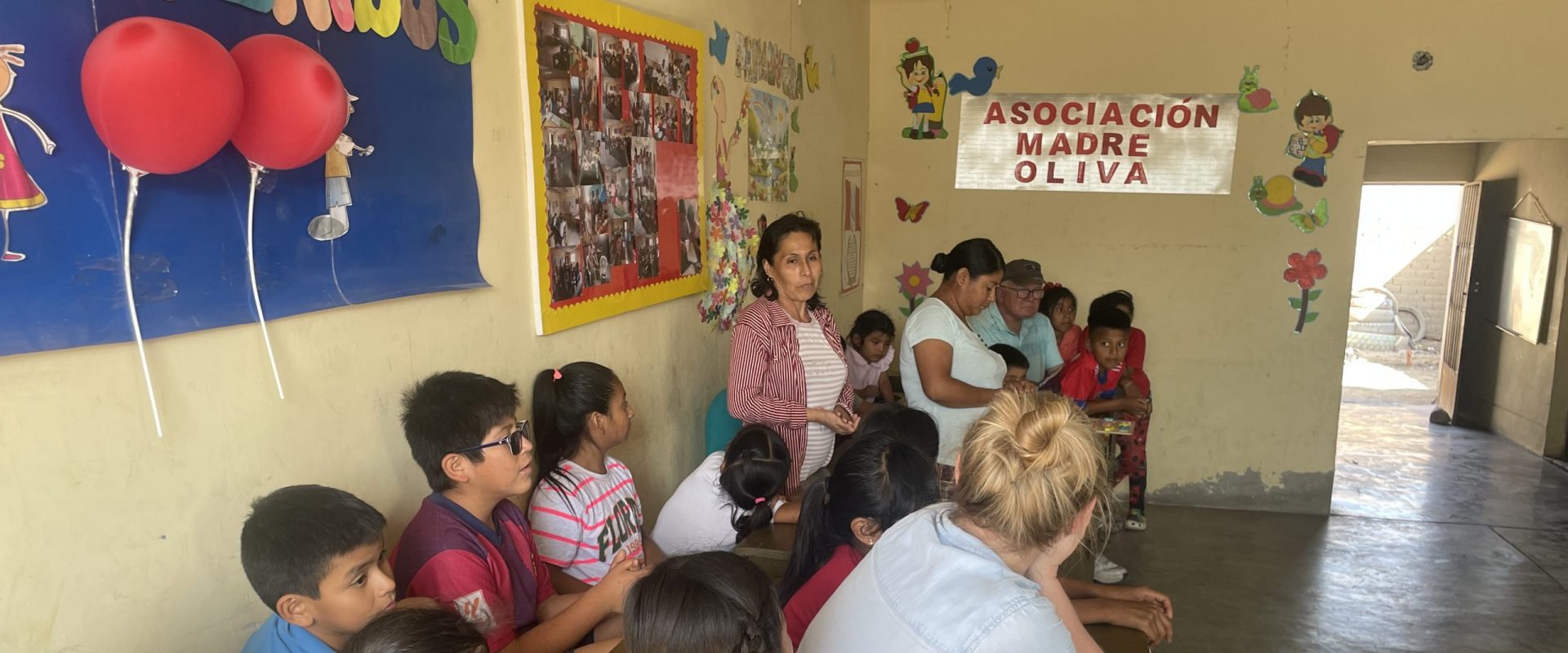 children sit at desks lined against one wall