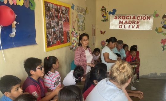 children sit at desks lined against one wall