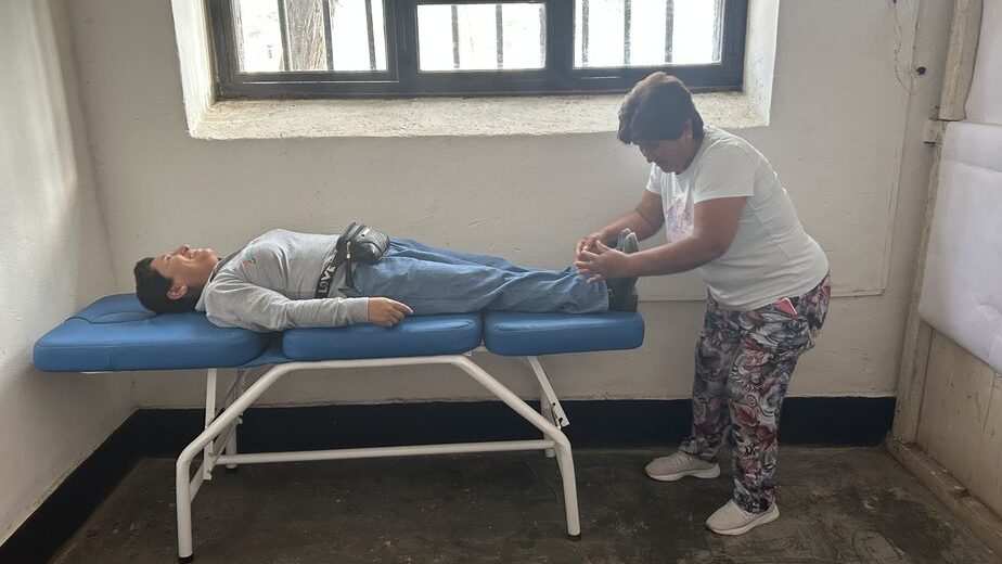 a woman lies on a cot while another woman massages her feet