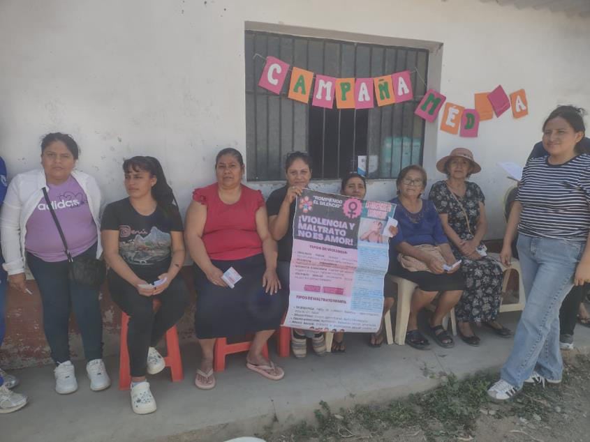 women sit and stand against a wall holding a sign calling for the end of violence against women