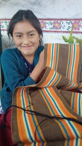 young woman holds up the weaving she made