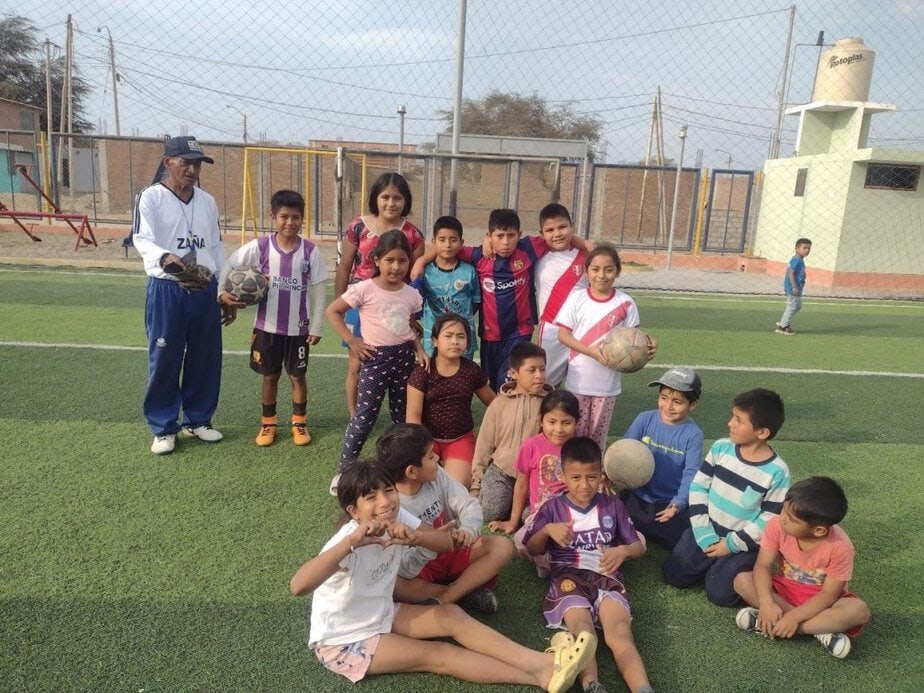 kids in soccer jerseys sit and stand on a playing field