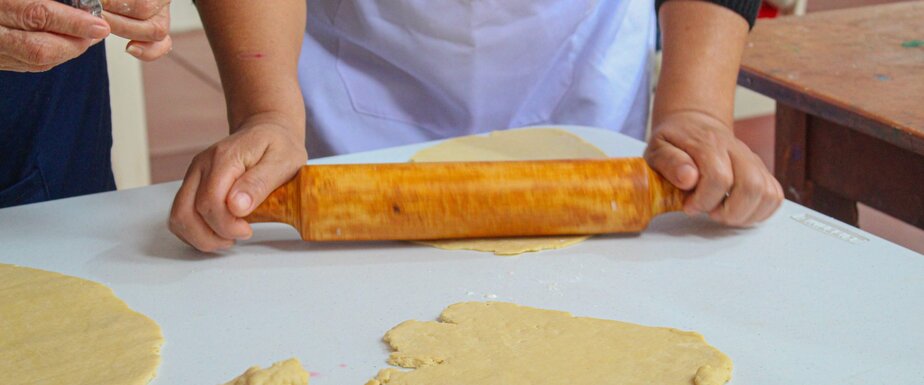the hands of a woman holding a rolling pin and the pasty she is rolling out