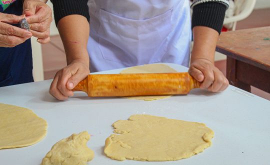 the hands of a woman holding a rolling pin and the pasty she is rolling out